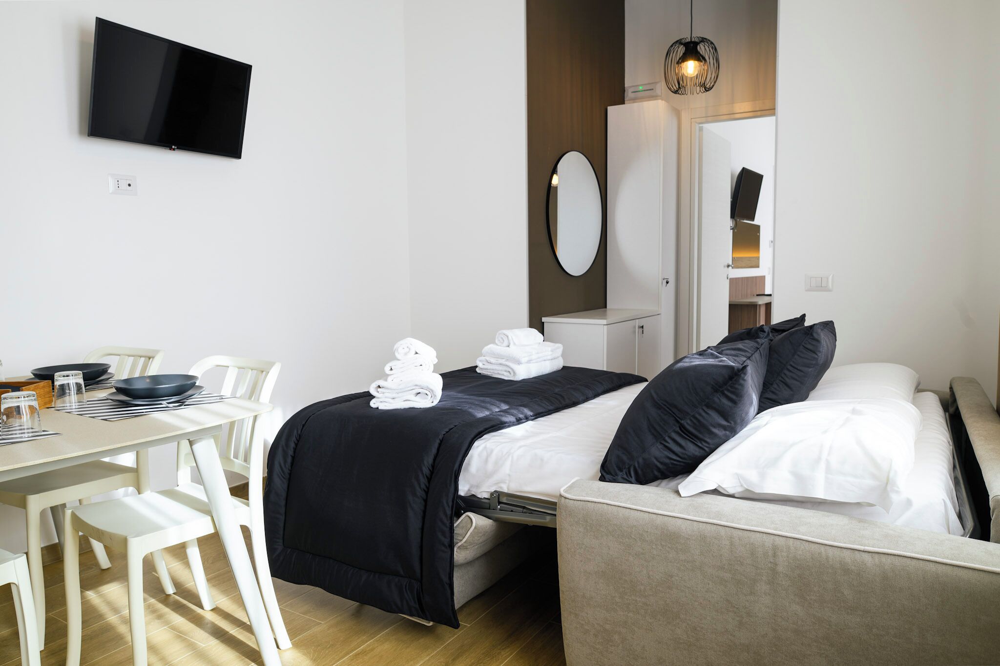 Et hotelværelse med seng, skrivebord med stole, et fladskærms-tv, et spejl og et garderobeskab.