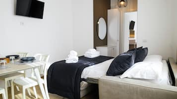 Et hotelværelse med seng, skrivebord med stole, et fladskærms-tv, et spejl og et garderobeskab.