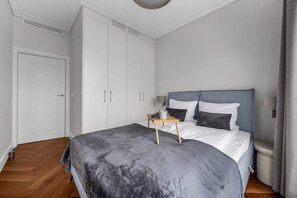 A bedroom with a bed, bedside table, and wardrobe. - Ochota Apt - Parking, Balcony & Railway Nearby (Warszawa)