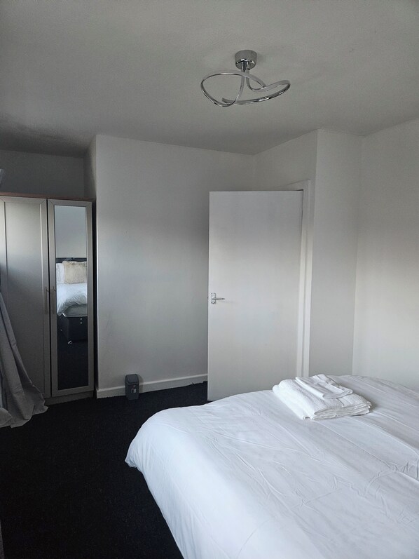 A hotel room with a bed, a wardrobe, and a door. - Relaxing and Comfort (Preston)