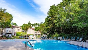 Ein rechteckiger Swimmingpool mit glasklarer, blauer Wasseroberfläche, umgeben von Liegestühlen und einer gepflasterten Terrasse.