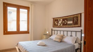 Ein Schlafzimmer mit einem Bett, einem Nachttisch, einer Wanddekoration und einem Fenster mit Vorhängen.