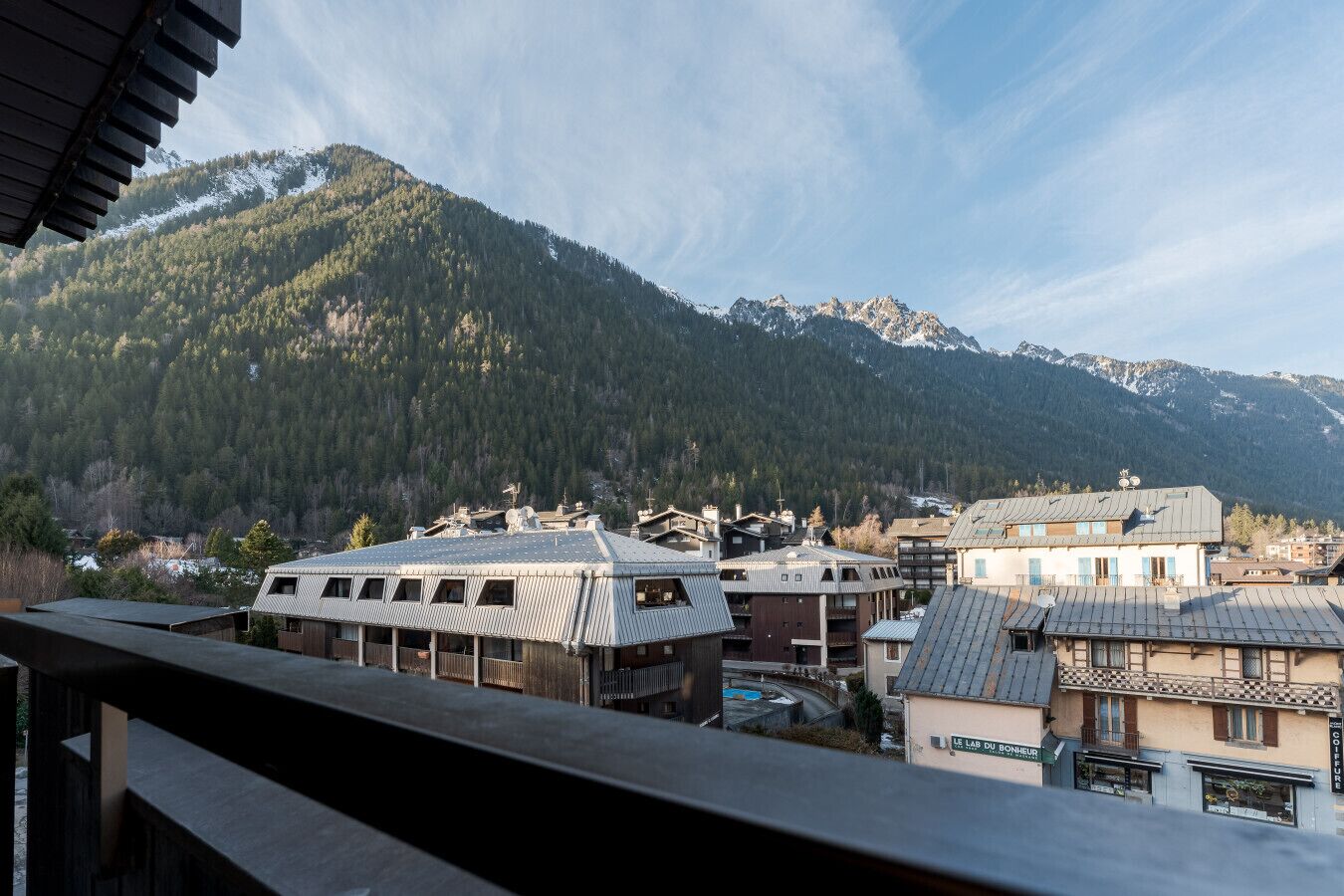 A mountain town with buildings featuring sloped roofs and a view of snow-capped mountains in the background.