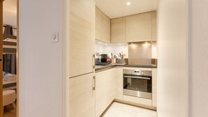 Eine kompakte Küche mit hellen Holzschränken, einem Edelstahlbackofen und einer Arbeitsfläche mit Küchenutensilien.