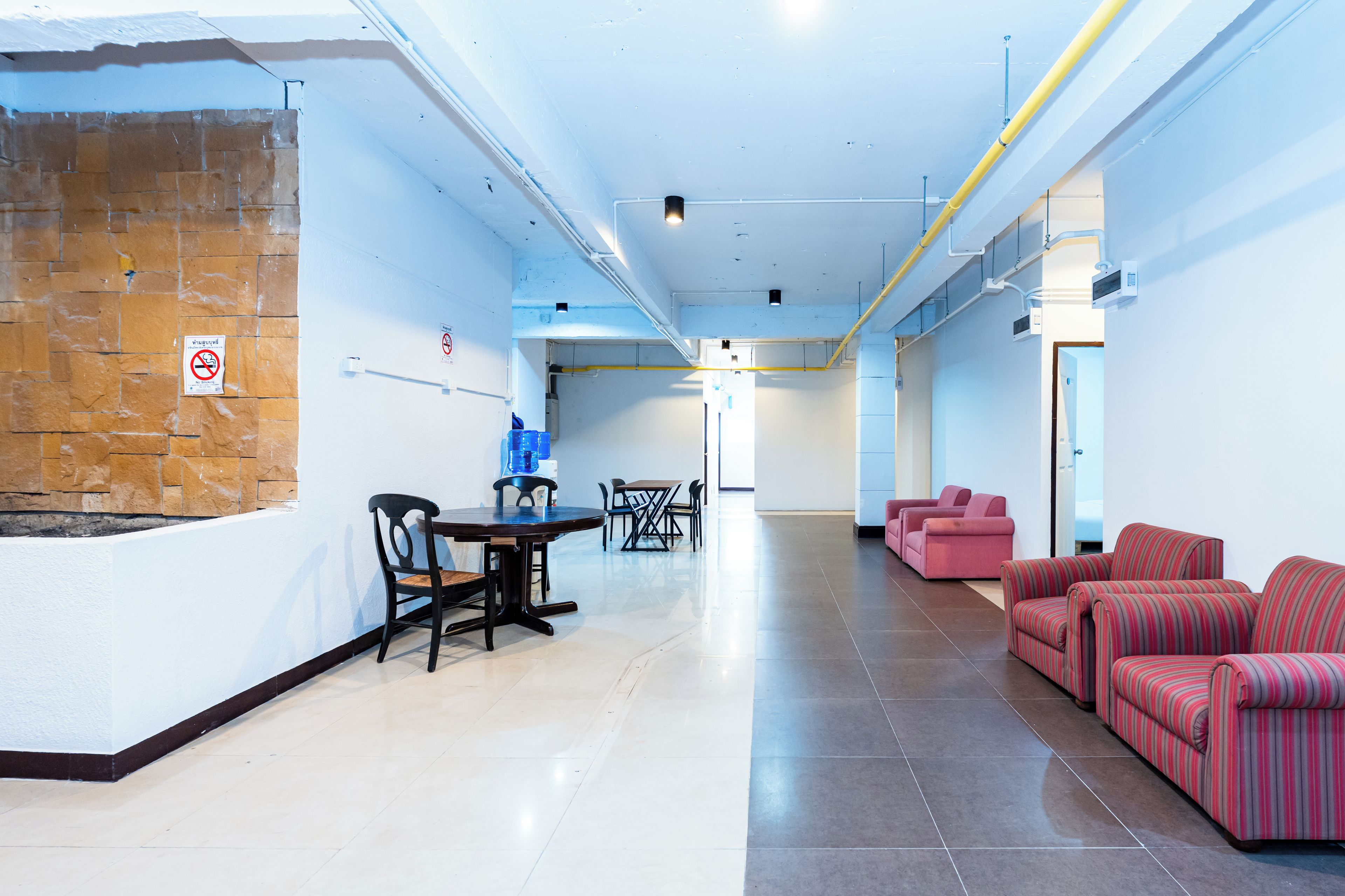 Amplo espaço interno com mesa e cadeiras para refeições, um bebedouro e uma área de estar com sofás.