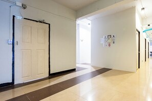A hallway with a door, a sign indicating room numbers, and a QR code for room reservations. - The Hidden Khaosan (Bangkok)