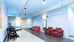 A spacious, modern lobby with a dining area, sofas, and a clear view of the hallway. - The Hidden Khaosan (Bangkok)