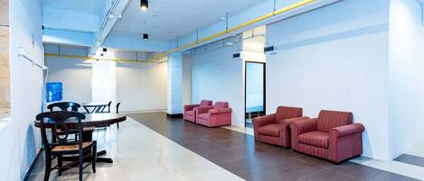 A spacious, modern lobby with a dining area, sofas, and a clear view of the hallway.