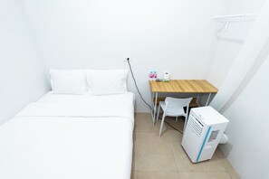A small, clean room with a bed, a desk, a chair, and a portable air conditioner. - The Hidden Khaosan (Bangkok)