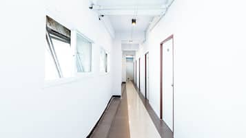 A corridor with white walls, a tiled floor, and doors on one side.