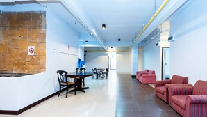 A spacious lobby with a dining area, sofas, and a stone accent wall. - The Hidden Khaosan (Bangkok)