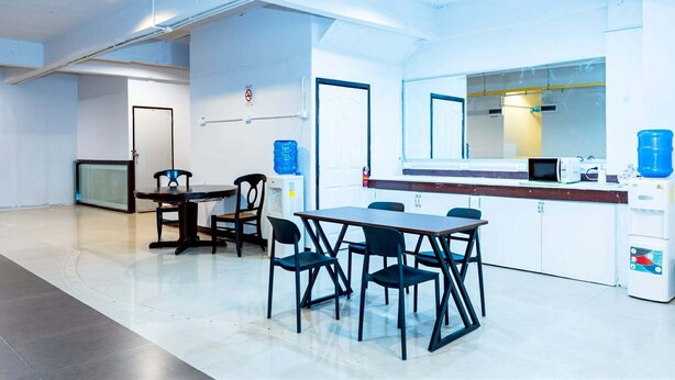 A modern kitchen with white cabinets, a microwave, and a water dispenser. - The Hidden Khaosan (Bangkok)