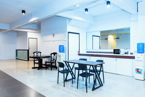 A modern office space with a round table, chairs, a water dispenser, and a microwave. - The Hidden Khaosan (Bangkok)