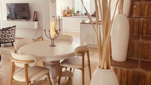 A dining area with a round table, chairs, and a vase with tall plants. - HACIENDA LAUTHI (Le Castellet)
