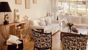 A living room with a white sofa, two patterned armchairs, a wooden console table, and a coffee table. - HACIENDA LAUTHI (Le Castellet)