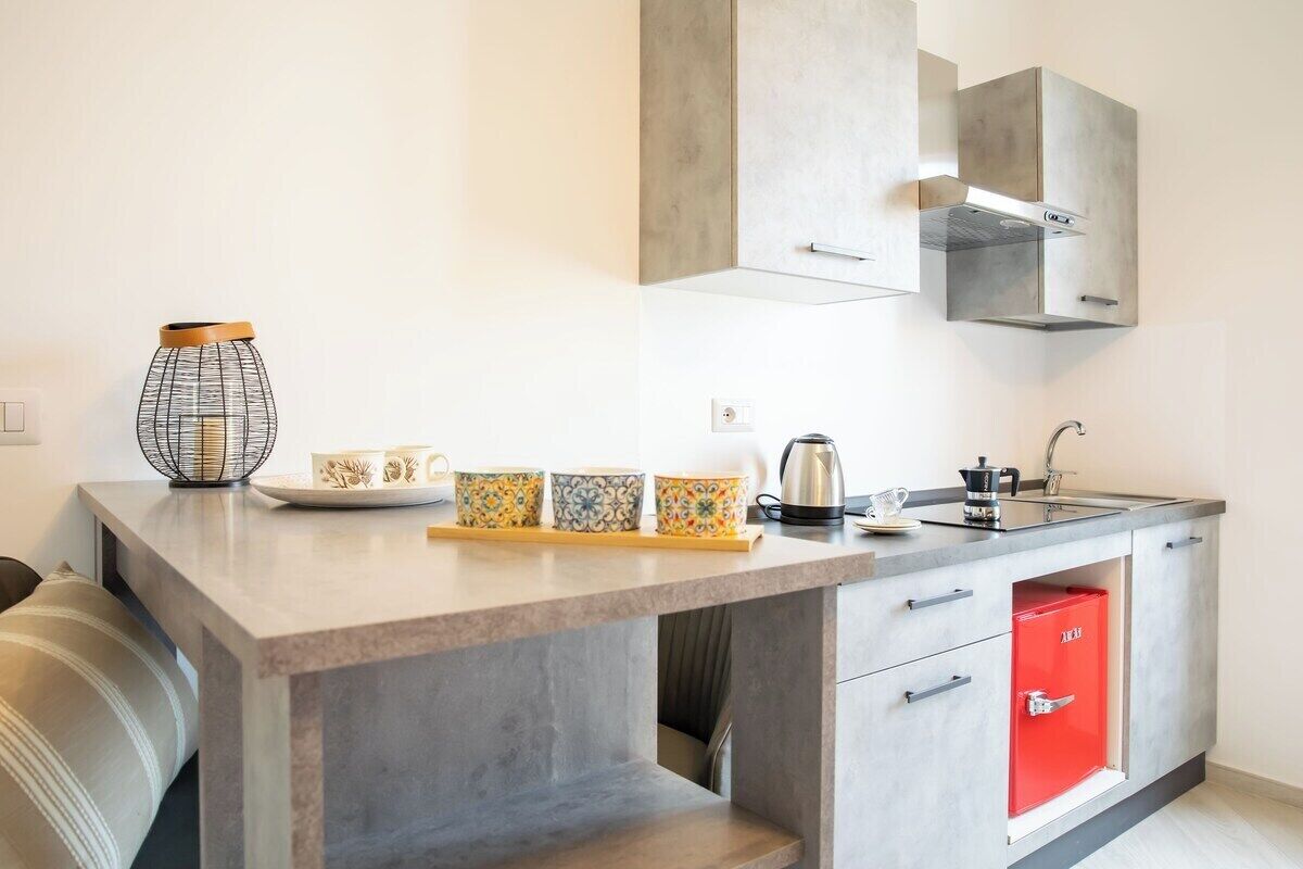 Eine moderne Küche mit grauer Arbeitsplatte, einer Kaffeemaschine und einem roten Schrank.