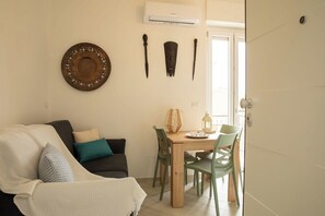 A cozy living room with a sofa, a dining table with chairs, and decorative items on the wall. - Apartments The Three Moons-New Moon (Alghero)