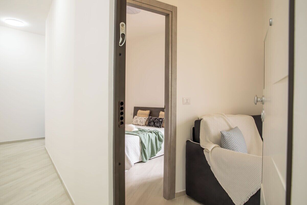 Una habitación de hotel con cama, una silla y una puerta que da a otra habitación.