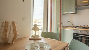 Een moderne keuken met een fornuis, oven en gootsteen. Er staat een eettafel met een dienblad met kopjes en een lantaarn.