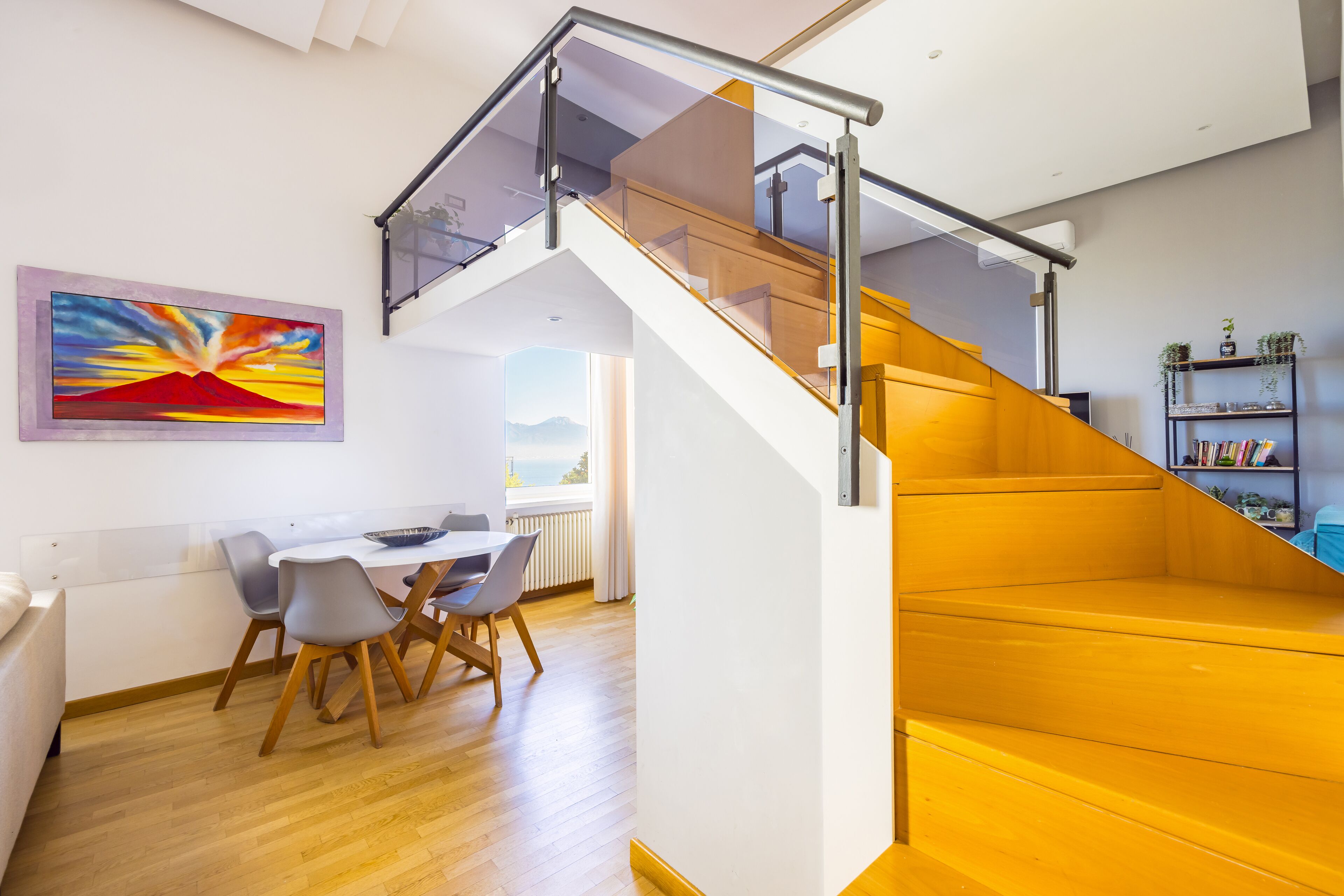 Un interior moderno con una escalera, comedor y estantería.