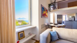 A modern living room with a sofa, a dining table, and a kitchen area. - Lite Life Panoramic Flat by Napoliapartments (Naples)