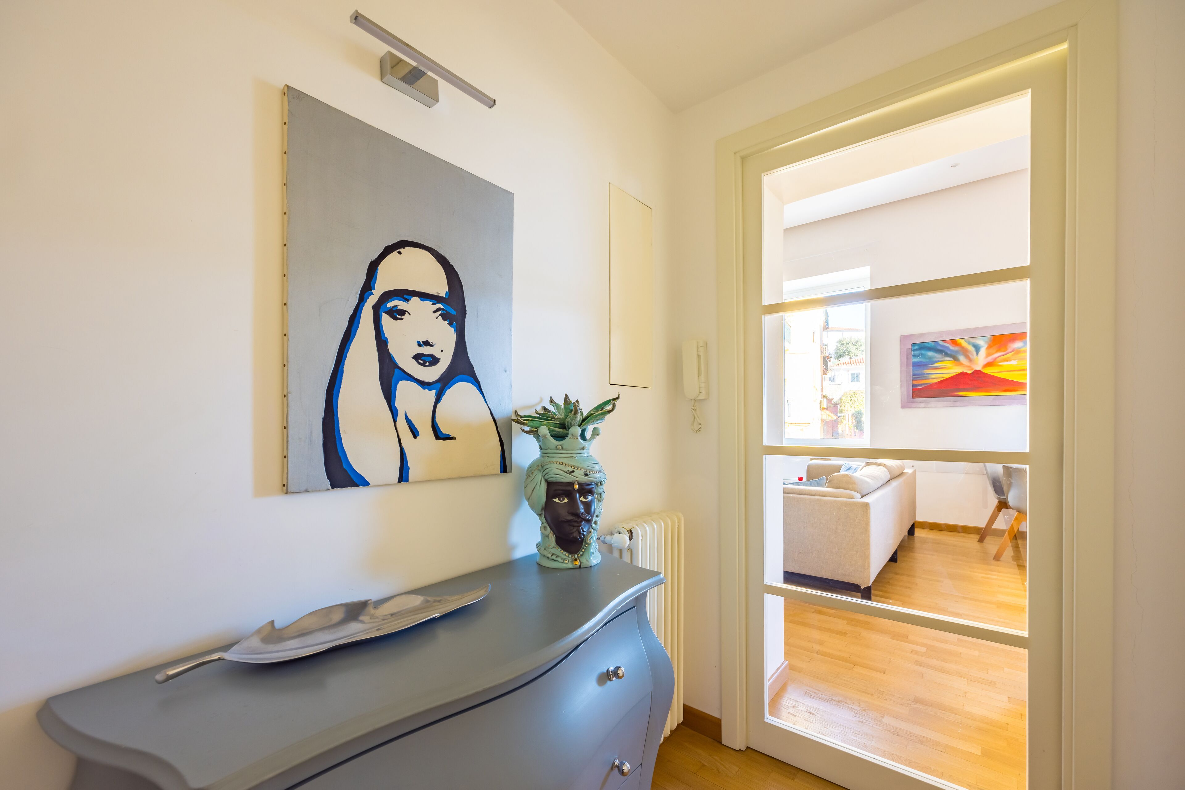 Een moderne woonkamer met een grijze bank, een salontafel en een groot schilderij aan de muur.