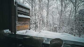 Eine Holzhütte mit einer Bank vor einer verschneiten Landschaft.