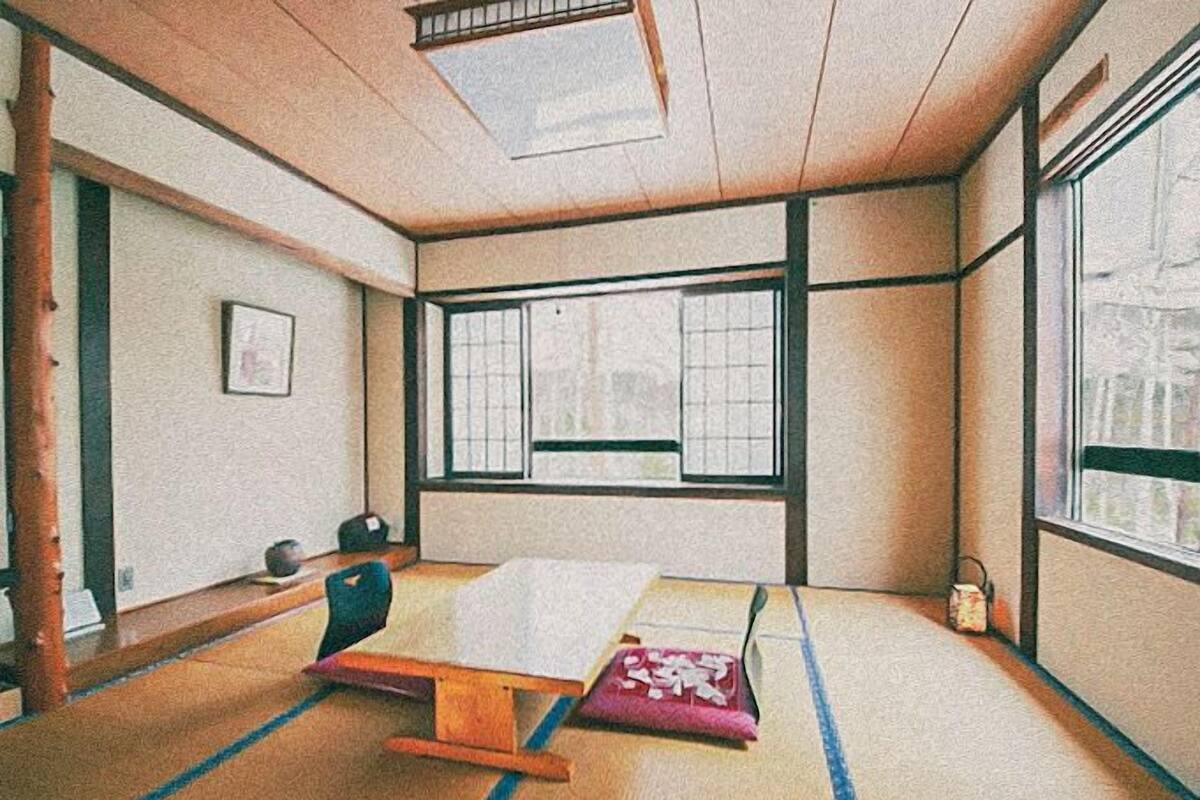 A tatami mat room with a futon bed, a shoji screen, and a view through the window.