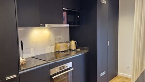 A compact kitchen with a microwave, stove, and a coffee maker. - Shell Living - KOS (Funchal)