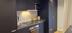 Une cuisine compacte équipée d’un four à micro-ondes, d’une cuisinière et d’une machine à café.