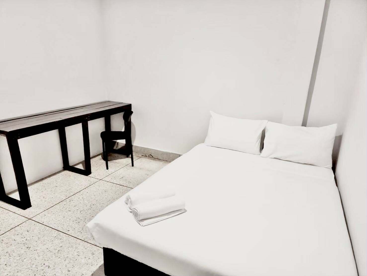 A minimalist room with a bed, a desk, and a chair.