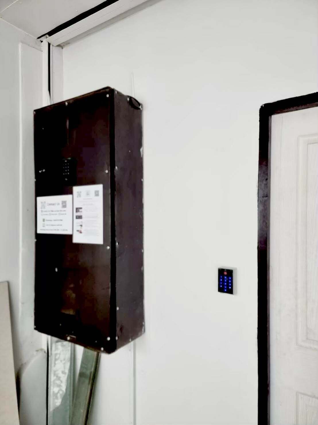 A utility box mounted on a white wall next to a door.
