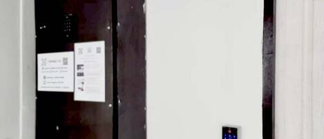 A utility box mounted on a white wall next to a door.