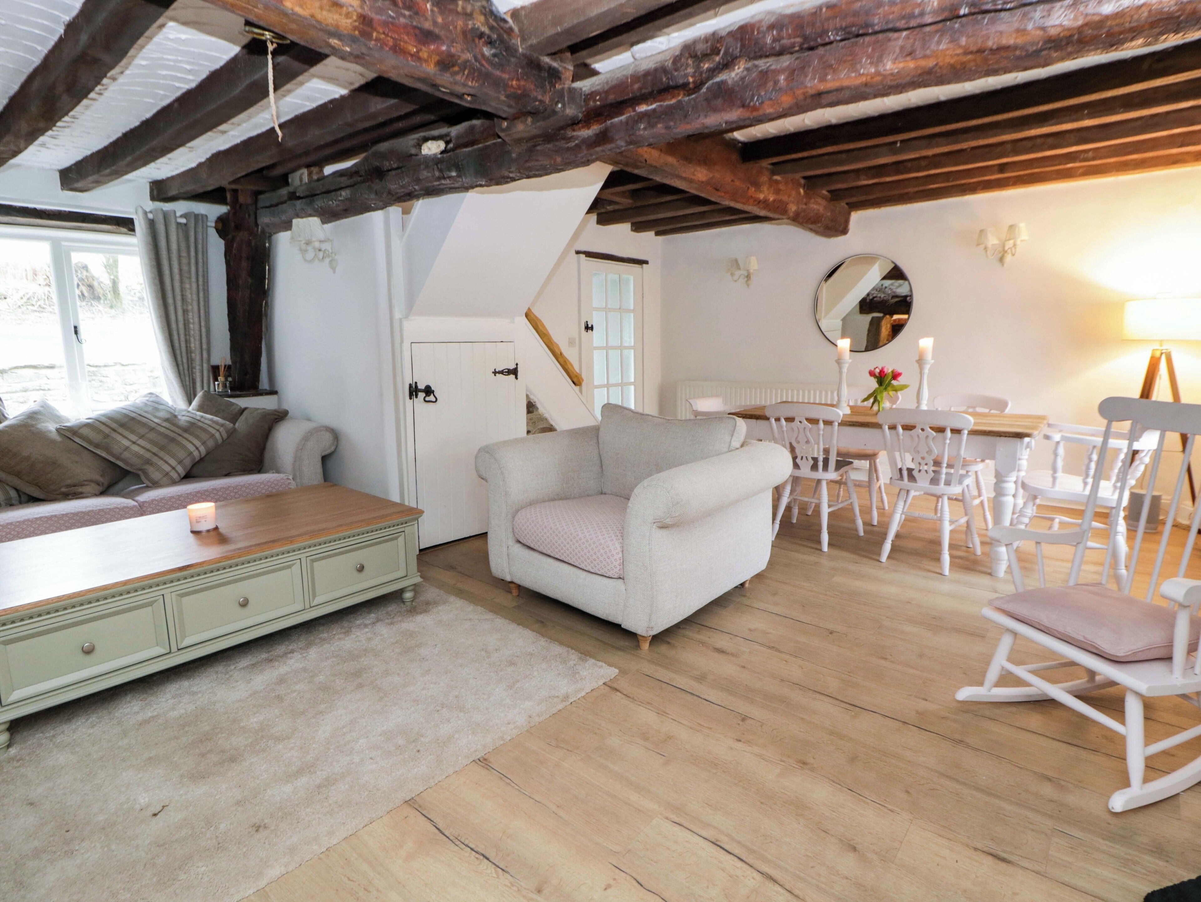 Una habitación acogedora con un sofá, una mesa de comedor con sillas, techo de madera y una puerta blanca.