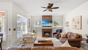 Un salón amplio con chimenea, sofás de cuero y ventilador de techo.