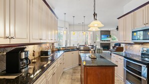 Una cocina amplia con una isla central, electrodomésticos de acero inoxidable y armarios de tonos claros.