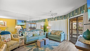 A living room with a sofa, ottoman, and a dining area with a table and chairs. - Arrowhead 210 in Kingston w/Elevator, Pool & beach (Myrtle Beach)