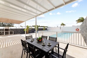 An outdoor patio with a table set for dining, a pool, and a white fence. - Casa Manuel by Escape Home (Playa Blanca)
