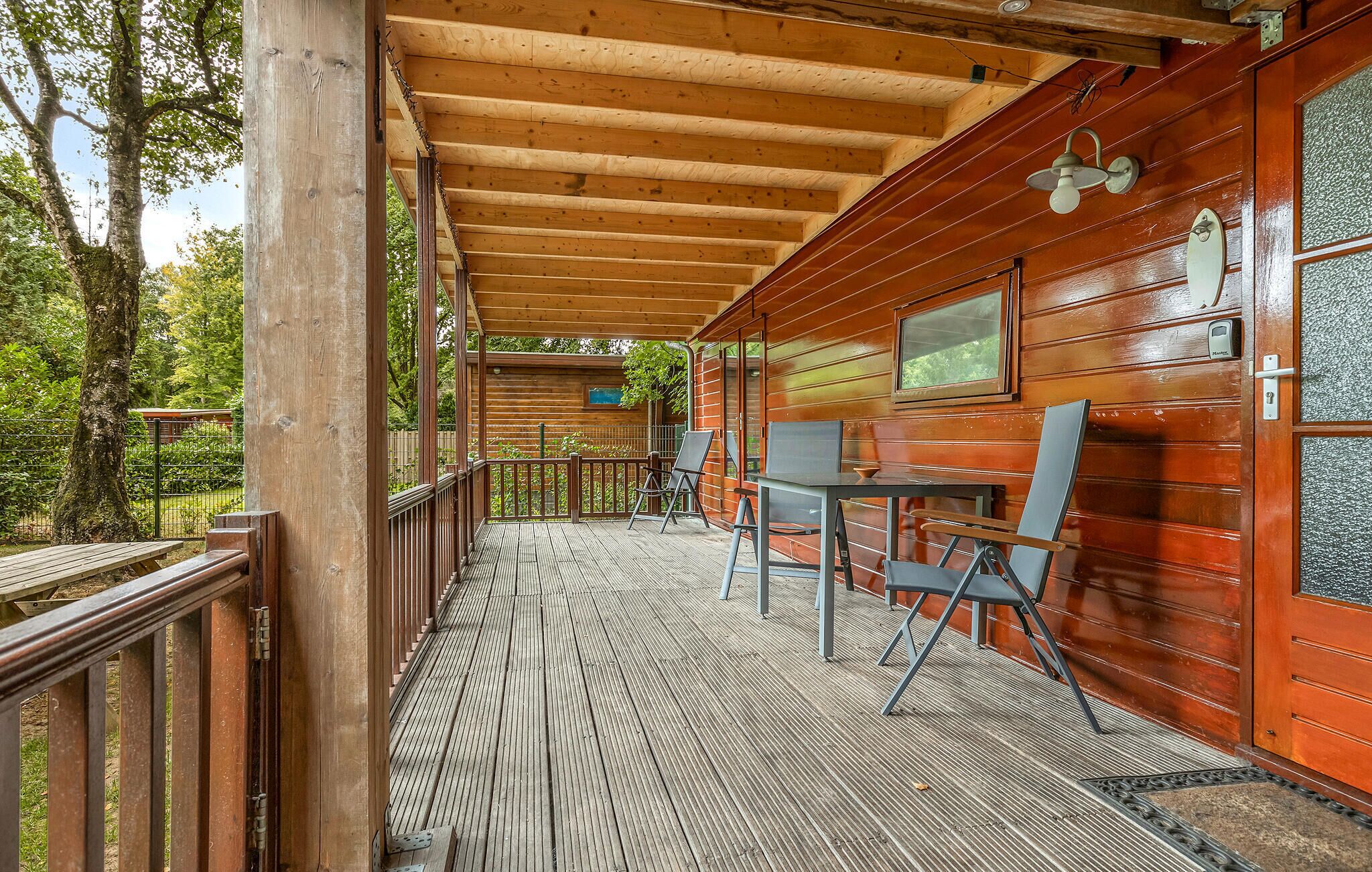 A wooden cabin with a covered porch, a table, and chairs.