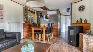 Un salon chaleureux avec une table en bois, un canapé en cuir noir et un coin repas avec des chaises en bois.