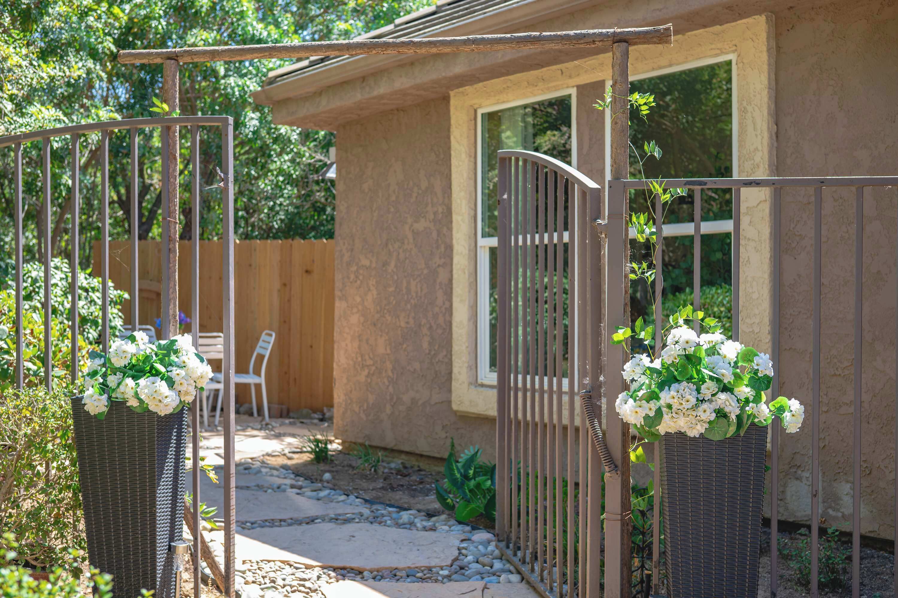 Un patio clos, agrémenté d’un chemin en pierre, d’une clôture en bois et d’une chaise blanche.