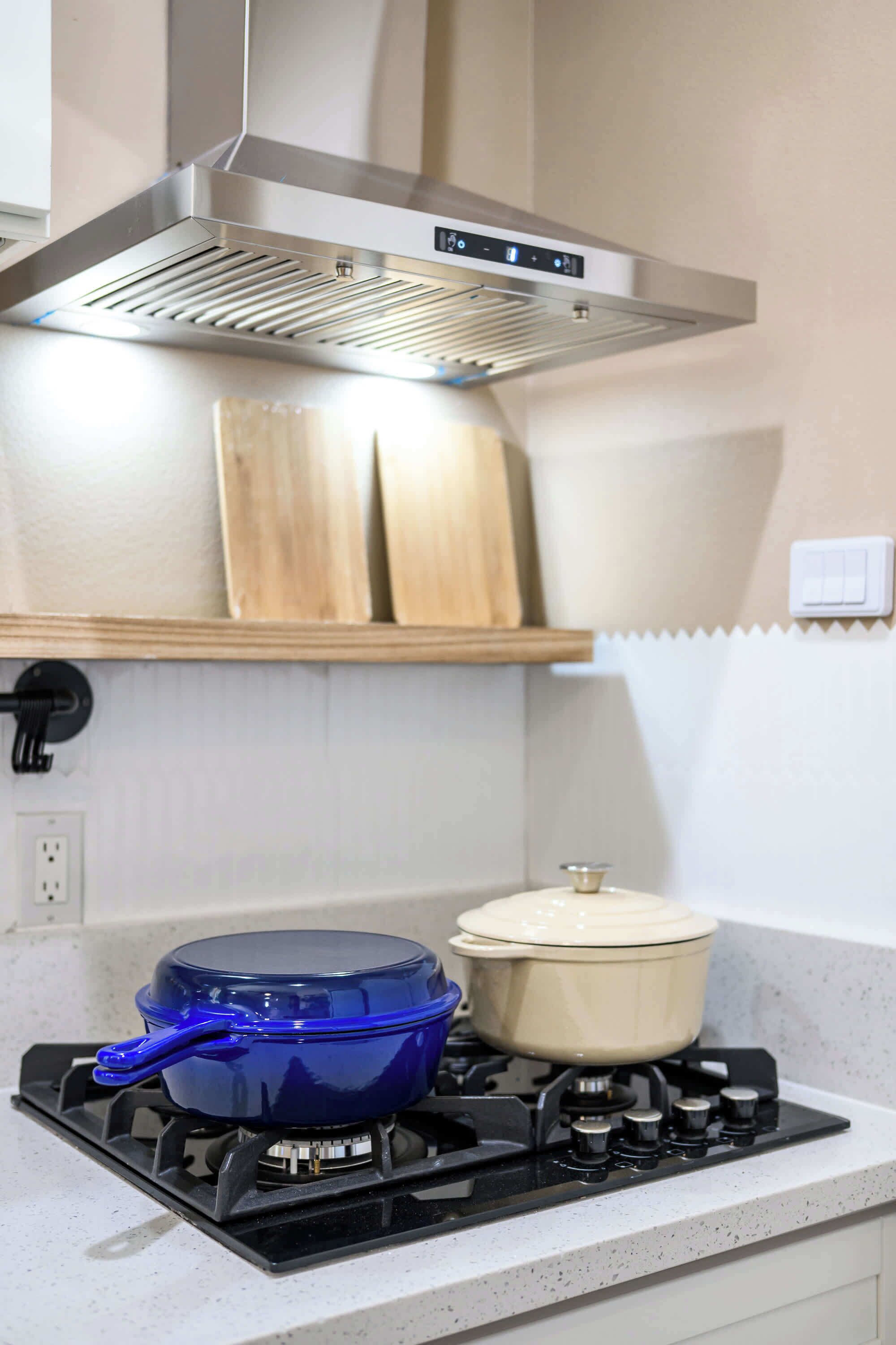 A kitchen with a stove, a blue pot, and a white pot on the counter.