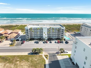 A multi-story hotel with a parking lot and a view of the ocean. - Beachfront Island Condo With Balcony Pool Grill (South Padre Island)