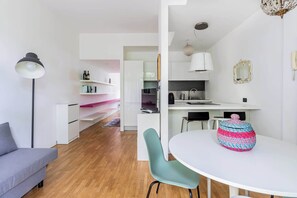 A modern kitchen with white cabinets, a dining table, and a colorful chair. - Casa Watt Stylish Apartment With Balcony (Milan)