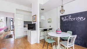 Een moderne keuken met een eethoek, een televisie, en een 'Welcome'-bord aan de muur.