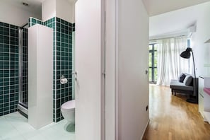 A modern bathroom with a shower, toilet, and a glass door leading to a bedroom. - Casa Watt Stylish Apartment With Balcony (Milan)