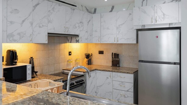 Eine moderne Küche mit Marmorkabinetten, einem Edelstahlkühlschrank und Granit Arbeitsplatten.