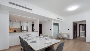 Ein moderner Essbereich mit einem Marmortisch und grauen Stühlen, eine Küche mit Backofen und Marmorkästen, und ein separater Arbeitsbereich mit Schreibtisch und Stuhl.