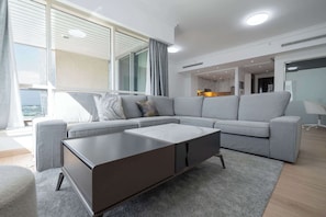 A modern living room with a grey sectional sofa, a dark coffee table, and a view of the city through large windows. - A Free Housekeeping Visit FOR Every Stay Between THE 16th FEB AND THE 16th MAR - Stayshort - Spacious 2 Bedroom in Dubai Marina That Sleeps 6 (Dubai)