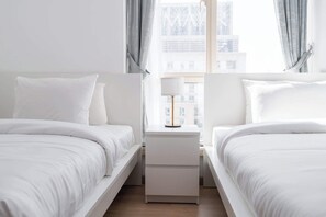 A hotel room with two beds, a nightstand, and a window with curtains. - A Free Housekeeping Visit FOR Every Stay Between THE 16th FEB AND THE 16th MAR - Stayshort - Spacious 2 Bedroom in Dubai Marina That Sleeps 6 (Dubai)